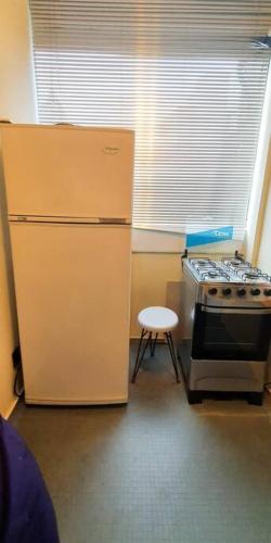 a kitchen with a refrigerator and a stove and a stool at Excelente apartamento en Plaza Independencia. in Montevideo