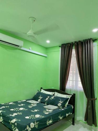 a green bedroom with a bed and a window at Sri Aman Homestay in Jitra