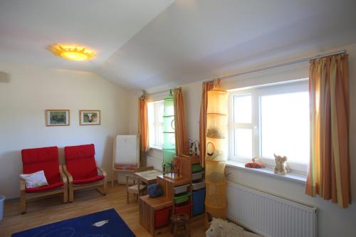 a living room with two red chairs and a window at Jugendherberge Dahme in Dahme