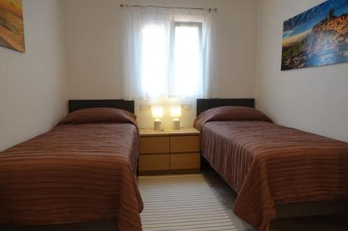 Duas camas num pequeno quarto com uma janela em Schönes Apartment mit Terrasse und Meerblick. em La Matanza de Acentejo