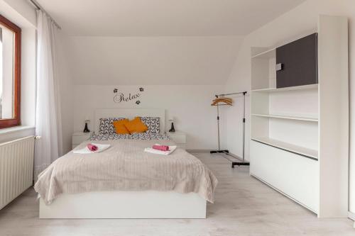 a white bedroom with a large bed with orange pillows at Apartment Mountain Sunrise in Škofja Loka