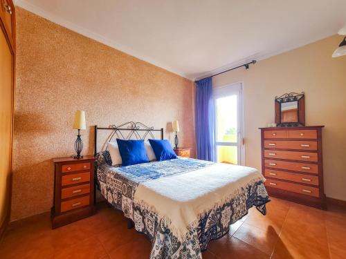 Un dormitorio con una cama con almohadas azules y una ventana en PARKING PRIVADO Benalbeach, en Benalmádena