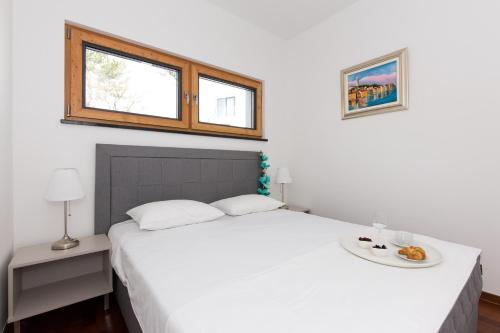 a bedroom with a white bed and a window at Villa Superior Two in Crikvenica