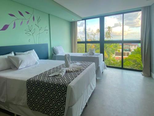 a bedroom with two beds and a large window at Pousada Amada Terra in Porto De Galinhas