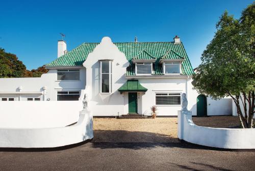 a white house with a green roof and a fence at Art Deco Coastal Apartment with Private Garden in Broadstairs