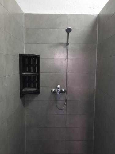 La salle de bains carrelée est pourvue d'une douche avec un tuyau. dans l'établissement Мандри Хостел, à Oujhorod