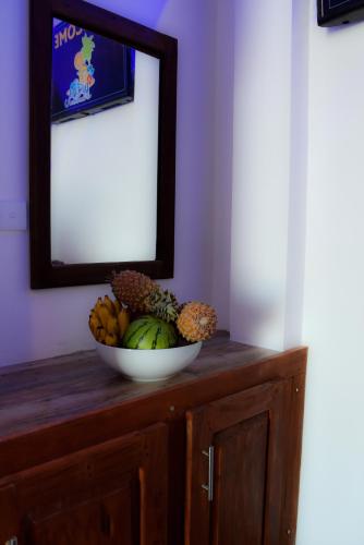 a bowl of fruit on a wooden cabinet with a mirror at Dinuda Resort in Kalpitiya