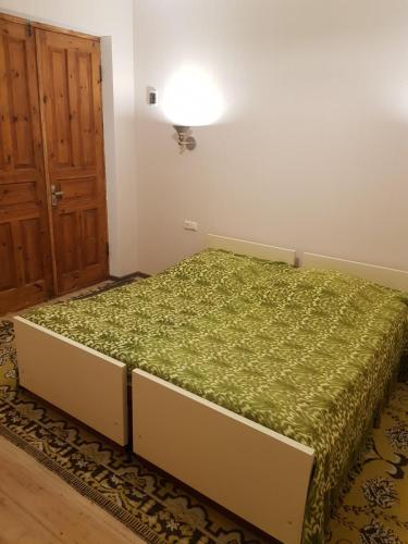 Tkhibuli geust house في Tqibuli: غرفة نوم بسرير وبطانية خضراء