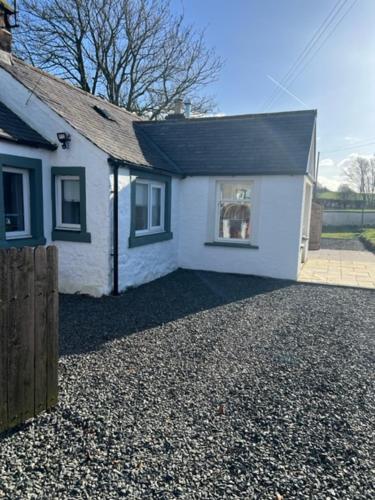 una piccola casa bianca con tetto nero di Cosy country cottage in rural location a Moffat