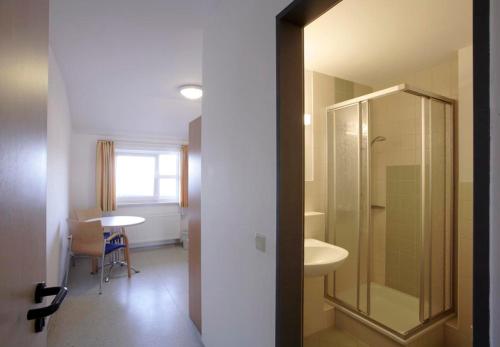a bathroom with a shower and a sink and a table at Jugendherberge Dahme in Dahme
