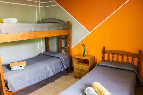2 literas en una habitación con pared de color naranja en Casa El Roble en San Rafael
