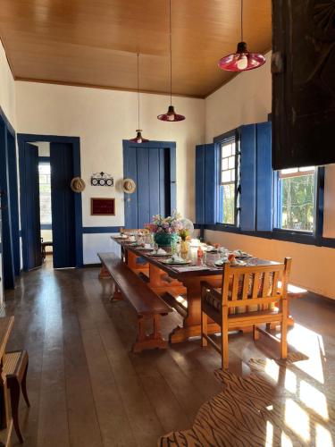 una sala da pranzo con tavolo, panche e armadi blu di Linda Fazenda Centenária a Santa Rita do Sapucaí