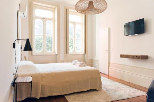 a bedroom with a bed and a flat screen tv at Alameda Suites - River Guest House in Porto
