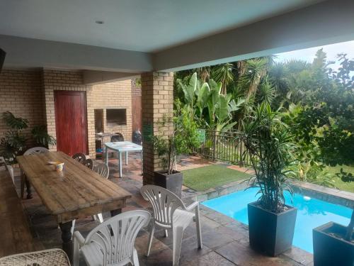 a patio with a table and chairs and a pool at Cove Rock Stay in East London