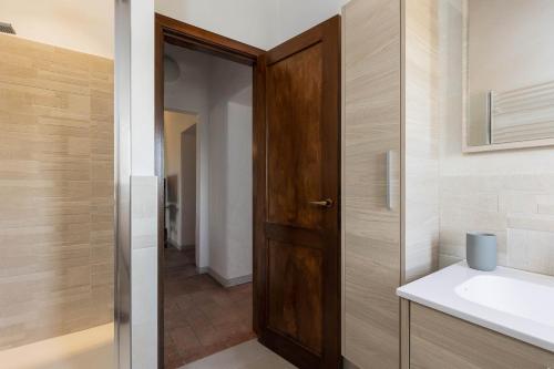 a bathroom with a wooden door and a sink at Poggio Vitignano Charming Cottage With Pool and Parking in Pianella