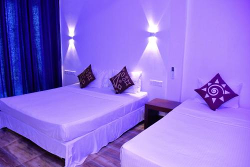 two beds in a hotel room with white sheets at Dinuda Resort in Kalpitiya