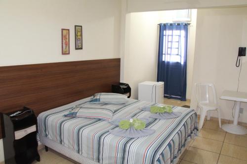 1 dormitorio con cama, mesa y lavamanos en Comfoort Hotel en Volta Redonda