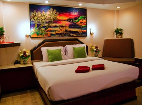a bedroom with a large bed with green and red pillows at Paradise Inn in Karon Beach