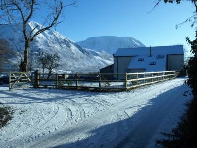 a snow covered road with a fence and a building at Damson Ghyll B&B in Loweswater