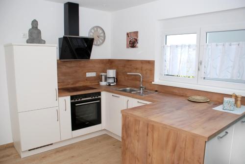 cocina con armarios blancos y encimera de madera en Ferienhof-Dachsberg Wohnung Paradies, en Bermatingen