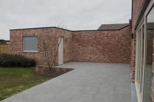 a brick wall with a patio next to a building at De Romanie in Mangelaar