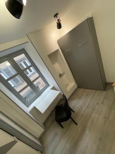 Habitación con ventana, silla y puerta en Ambert CentreVille La Studette tout confort, en Ambert