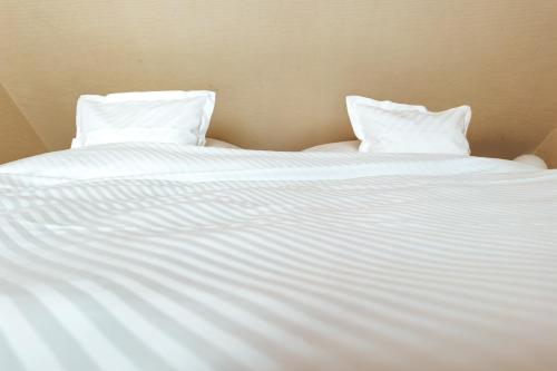 Una cama blanca con dos almohadas encima. en Gästehaus Röll - Wohnung 3, en Norderney