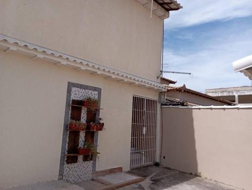 un bâtiment blanc avec une porte avec des plantes. dans l'établissement LAGOA II SAQUAREMA RJ, à Saquarema