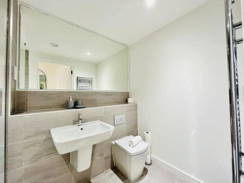 W łazience znajduje się umywalka, toaleta i lustro. w obiekcie Modern one bedroom apartment near Old Trafford Stadium w Manchesterze