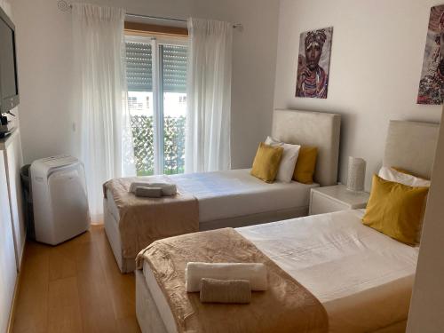 een hotelkamer met twee bedden en een raam bij Apartamento Altumar T2 in Portimão