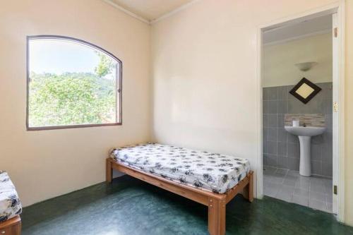 um quarto com uma cama, um lavatório e uma janela em Casa com 6 Suites, piscina e estacionamento em Ilhabela