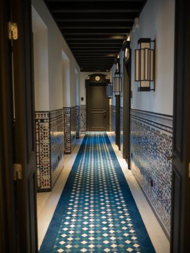 a corridor of a building with blue tiles on the floor at Hotel Casa Palacio Don Ramón in Seville