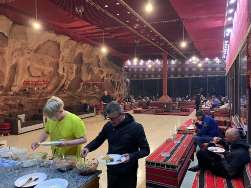 a group of people eating food in a large room at Wadi Rum Travel camp in Wadi Rum