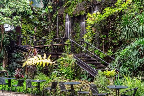 a stairway with tables and chairs in front of a waterfall at 515 VICTORY Hotel in Pom Prap