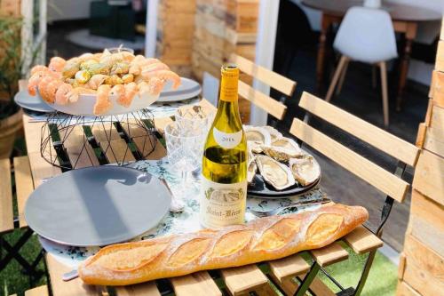 a table with a bottle of wine and a plate of food at Le Gambetta - La Rochelle Royale in La Rochelle