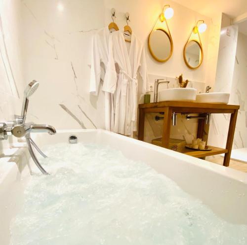 a white bathroom with a tub and a sink at Le Gambetta - La Rochelle Royale in La Rochelle