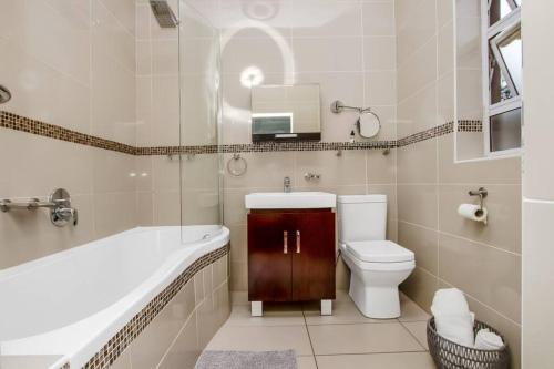a bathroom with a tub and a toilet and a sink at Paradise Guest House in Roodepoort