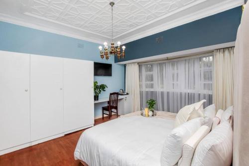 a bedroom with a white bed and a desk at Paradise Guest House in Roodepoort