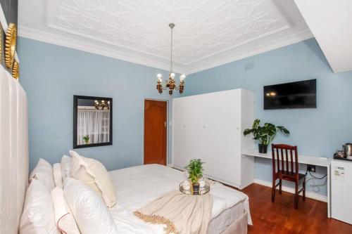 a bedroom with a white bed and a table at Paradise Guest House in Roodepoort
