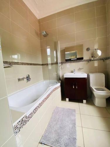 a bathroom with a tub and a toilet and a sink at Paradise Guest House in Roodepoort