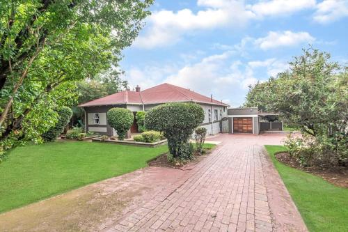 a house with a brick driveway in front of a yard at Paradise Guest House in Roodepoort