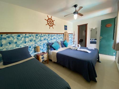 a bedroom with two beds and a ceiling fan at Pousada Cantinho do PÊ Guarujá in Guarujá