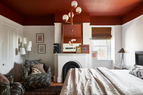 a bedroom with a bed and a chair and a fireplace at Blind Tiger Portland - Carleton Street Guest House in Portland