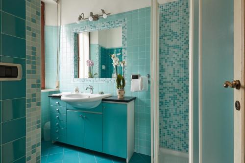 La salle de bains bleue est pourvue d'un lavabo et d'un miroir. dans l'établissement Le Balze Camere in Villa, à Pérouse