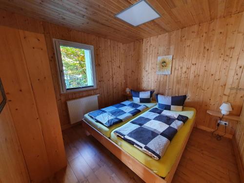 a bedroom with a bed in a wooden room at Ferienhäuser & Bungalows - Naturcamp Meyersgrund im Thüringer Wald in Ilmenau