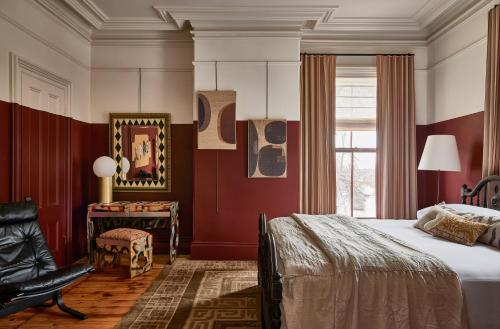 a bedroom with red walls and a bed and a chair at Blind Tiger Portland - Carleton Street Guest House in Portland