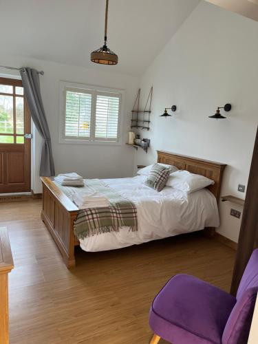 een slaapkamer met een groot bed en een paarse stoel bij The Crown Lodges in Deal