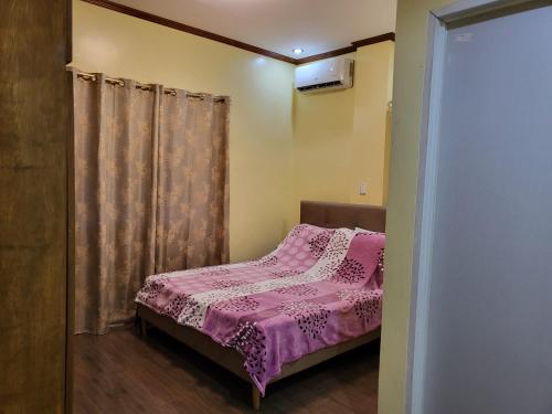 a small bedroom with a bed with a pink bedspread at Yuke's Bed & Breakfast in Valencia