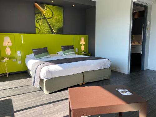 1 dormitorio con 1 cama grande y pared verde en Golf Hotel Colvert - Room Service Disponible, en Levernois