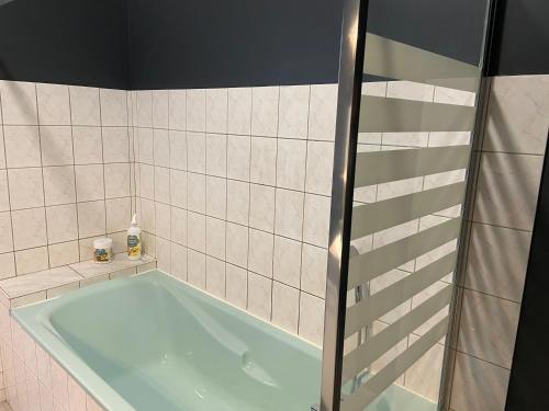 La salle de bains carrelée est pourvue d'une baignoire. dans l'établissement Le Chic Vintage, à Contrexéville
